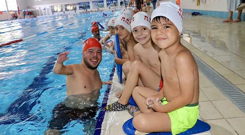 Ortopedik engelli antrenör çocuklara yüzme öğretiyor