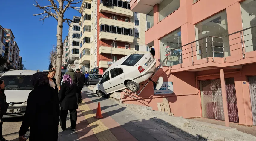 Park halindeyken geri kaçan otomobil binanın merdivenlerinde asılı kaldı
